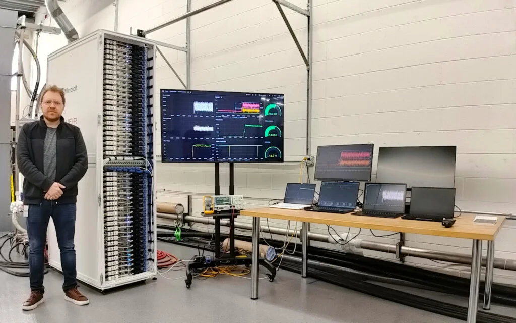 Ruslan Nagimov, principal infrastructure engineer for Cloud Operations and Innovation at Microsoft, near world’s first HTS-powered rack-prototype (superconducting line seen above the rack)